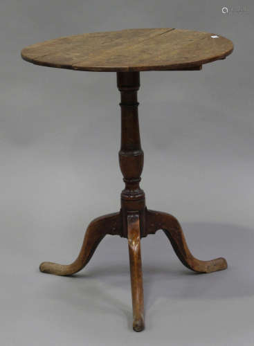 An 18th century oak tip-top circular wine table, raised on a turned column and tripod cabriole legs,