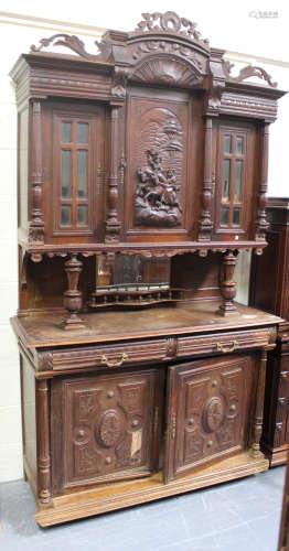 An early 20th century French oak buffet, the top section with carved and glazed doors above a