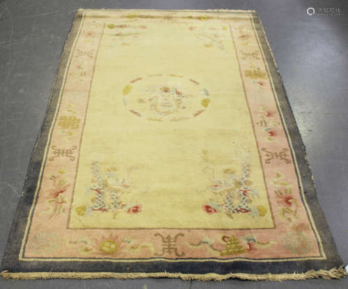 A Chinese rug, mid-20th century, the ivory field sparsely decorated with dragons, within a pale pink