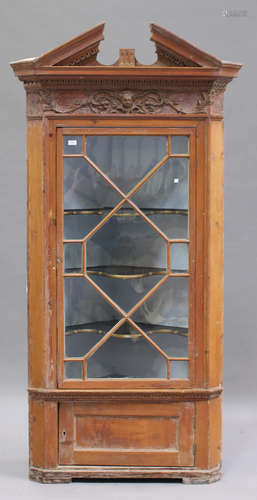 A 19th century pine architectural corner cabinet, the break arch pediment above a mask and scroll