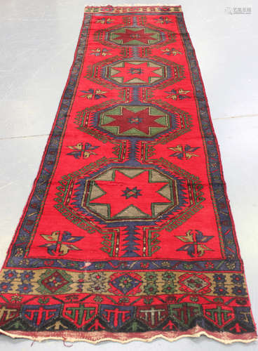 A Turkish runner, early/mid-20th century, the deep red field with a column of four linked