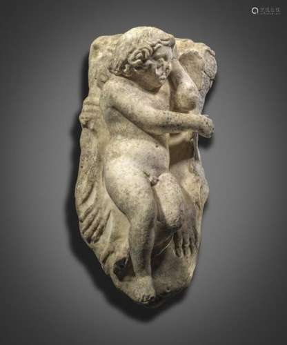 A carved marble figure of Eros sleeping, lying on …