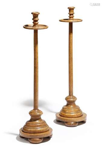 A pair of turned oak candlestands, each with an ur…