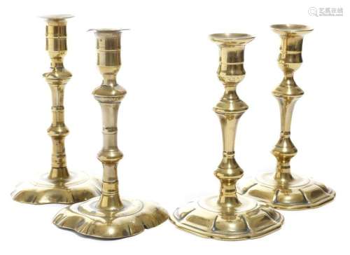 Two pairs of George II brass candlesticks, with kn…