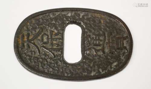 A Japanese iron tsuba, oval form cast with calligraphy mark, 9cm wide.