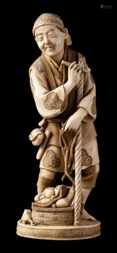 A Japanese carved ivory okimono of a peasant: standing holding a pipe in one hand and a staff in