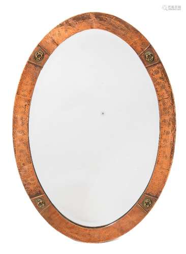 An oval copper framed wall mirror in the Arts & Crafts taste: the mirror plate enclose by a beaten