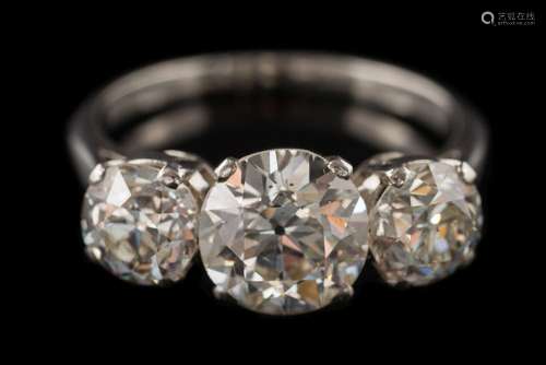 A diamond three-stone ring: the principal old European-cut diamond approximately 7.9mm diameter x 4.