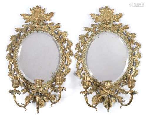 A pair of brass Girandole mirrors: with oval bevelled mirror plates,