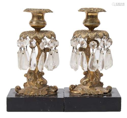 A pair of 19th century gilt brass candlesticks: in the form of dolphins, with urn-shaped nozzles,