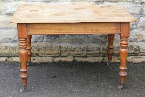 A Scrubbed Pine Kitchen Table: the table having a cutlery drawer, turned legs on casters, approx 124 x 91 x 76 cms