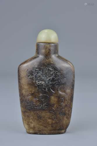 A Chinese brown pale jade snuff bottle with incised decoration of trees with pale green jade stopper