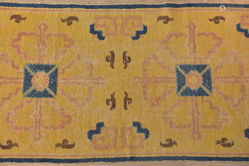 A late 19th century Tibetan prayer rug yellow ground with blue border decorated with two Buddhist sy