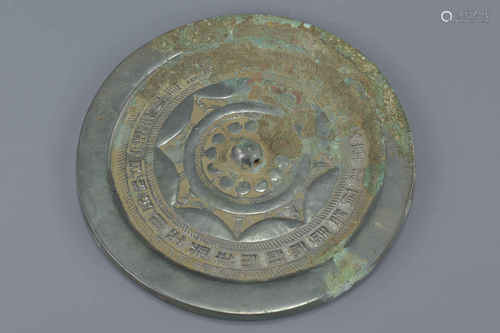 A Chinese Han dynasty or later circular bronze mirror with inscriptions and symbols with some burial