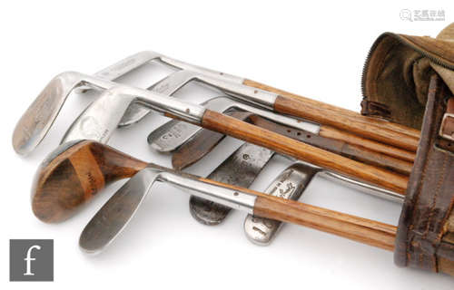 A collection of ten early 20th Century hickory shafted golf clubs, irons and woods with a canvas bag. (10)