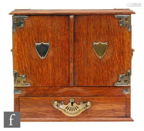 A late 19th to early 20th Century oak smokers cabinet with plated mounts and with twin carry handles to the sides, the double doors opening to reveal a fitted base drawer with two further drawers above, height 29cm, width 31cm and depth 22cm, S/D.