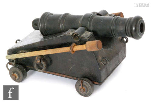 A late 19th to early 20th Century bronze cannon on black painted metal carriage with two mounted ram rods to each side, length of barrel, length 26cm.