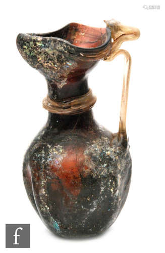 Roman 2nd to 4th Century AD - An iridescent deep amber glass jug with applied clear ribbed handle, A/F, height 13cm