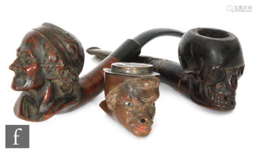 A briar pipe, the bowl carved as a portrait of Voltaire after Jean Antoine Houdon, together with another carved as a skull with hallmarked silver collar and a bowl in the form of an African gentleman's head with a white metal hinged lid formed as a hat, A/F (3)