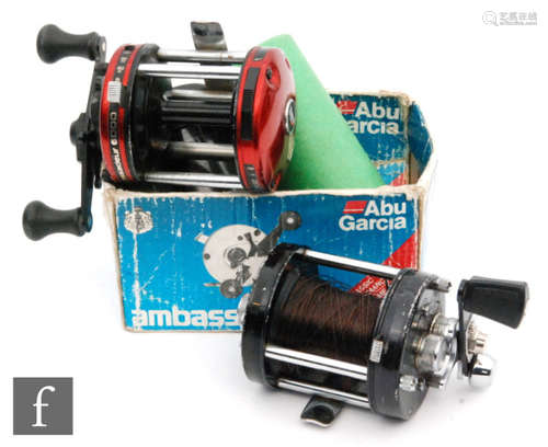 An Abu Ambassadeur 6000 bait casting multiplying reel, black paint finish worn through use, also a later Abu-Garcia Ambassadeur reel, red paint finish, in box, two spare spools. (4)