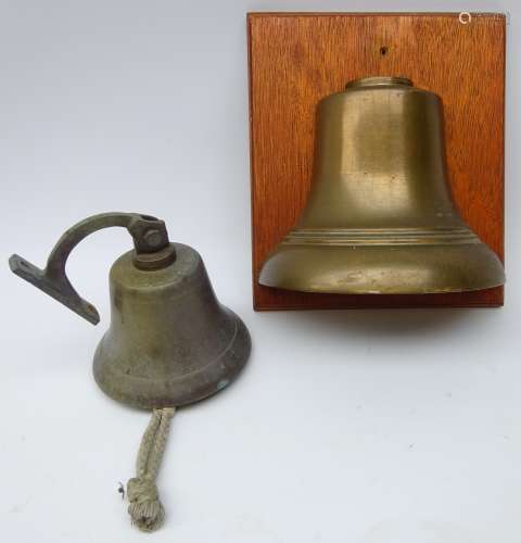 Brass bell on wall bracket and a half mounted school bell on displayed on oak panel,