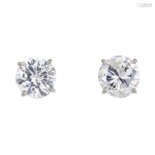 A pair of brilliant-cut diamond stud earrings. Total