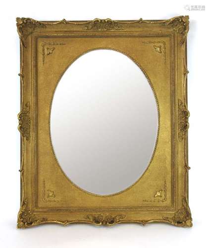 A 20th century oval mirror with a rectangular gilt frame,