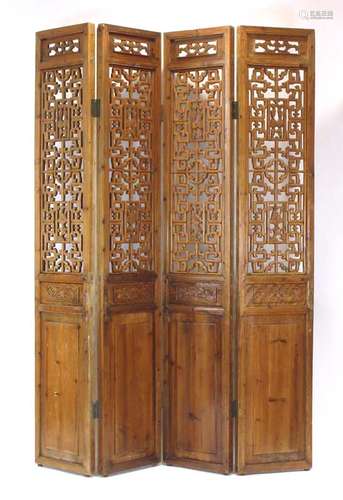 A late 19th century Chinese elm four section screen, typically carved with foliate motifs,