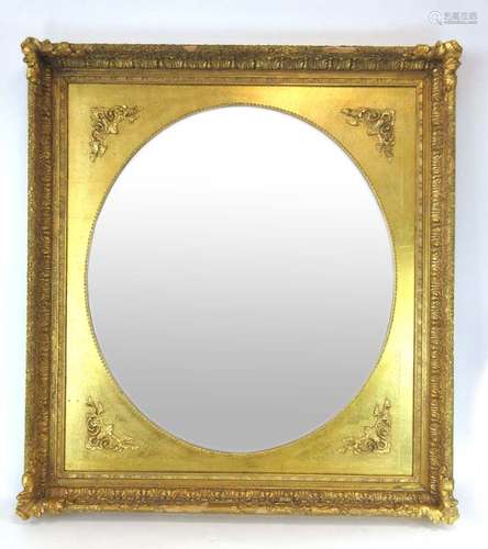 A 20th century oval mirror within a rectangular gilt border,