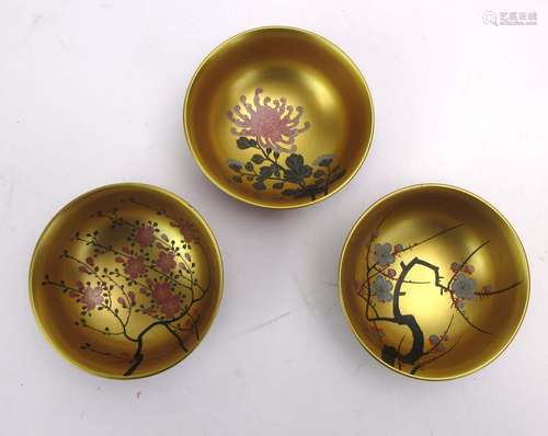 A set of three Japanese lacquered bowls, each internally gilt decorated with a blossoming shrub, d.