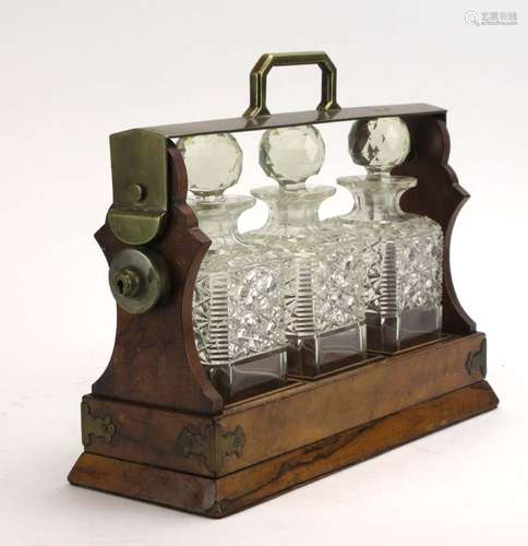 A Victorian walnut and brass mounted tantalus containing three cut glass decanters and stoppers