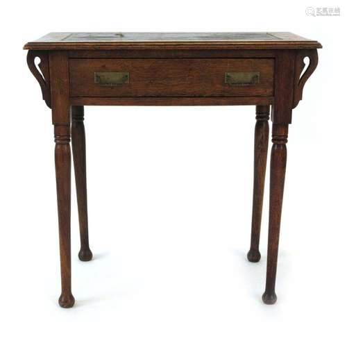 A Commercial Arts & Crafts oak writing table with a tooled leather surface over a frieze drawer,