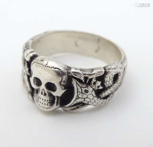 A silver ring with skull and serpent decoration, in the