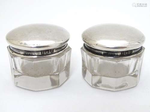 A pair of glass pots with silver tops hallmarked