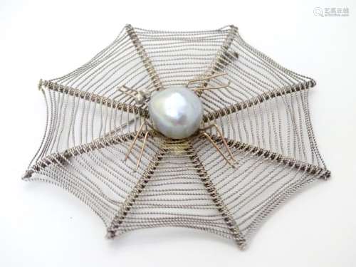 A silver brooch formed as a spiders cobweb with spider