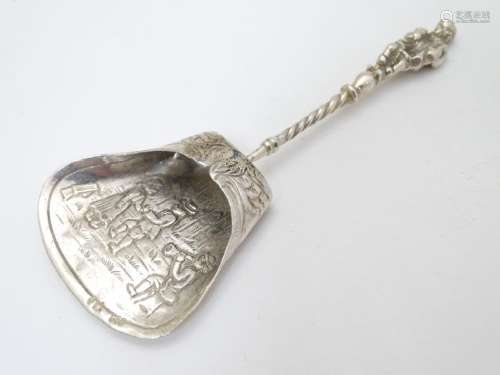 A Continental white metal caddy spoon depicting figures