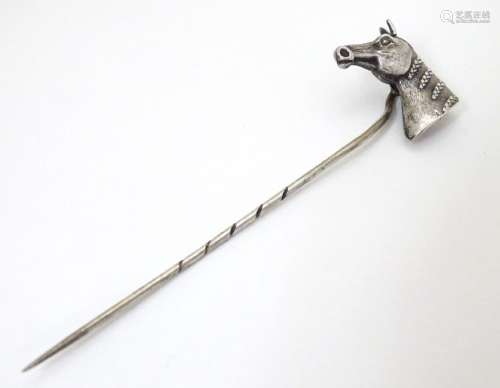 A white metal stick pin surmounted by a horses head.