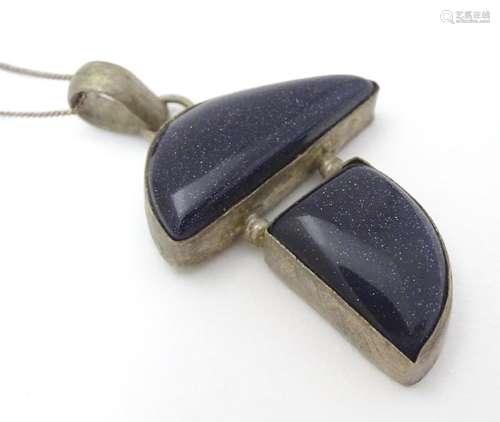 A modernist pendant set with polished hardstone detail