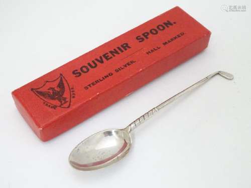 A silver teaspoon with handle formed as a golf club.