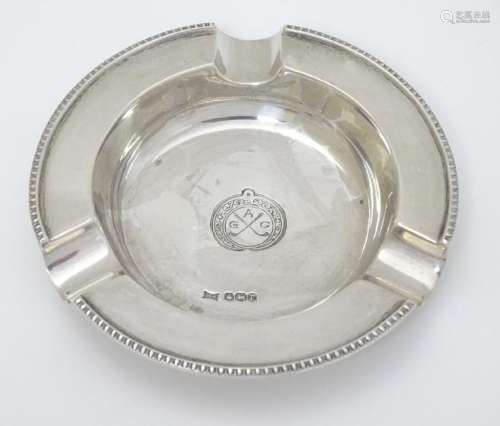 A silver ash tray with engraved crossed golf club