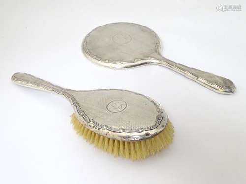 A silver backed hand mirror and brush with engine