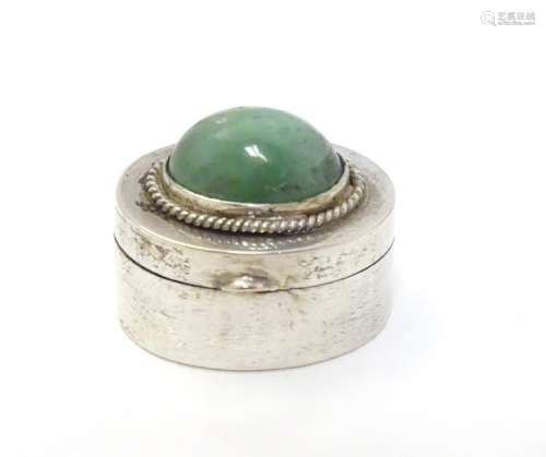 A white metal pill box of oval form with jade cabochon