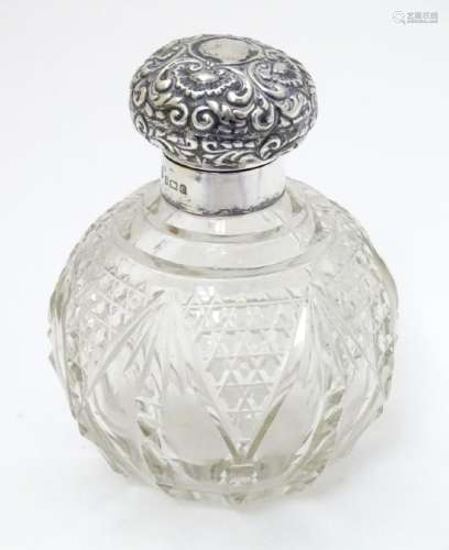 A cut glass scent / perfume bottle with silver top