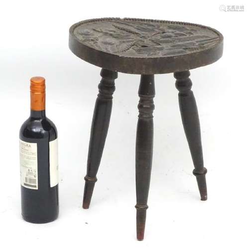 A 19thC circular three legged stool with carved seat