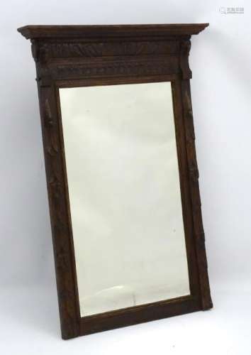 An early 20thC oak mirror with moulded cornice above