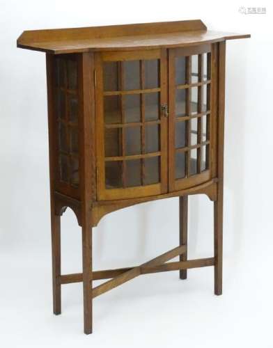 Arts & Crafts: An oak bow fronted display cabinet /