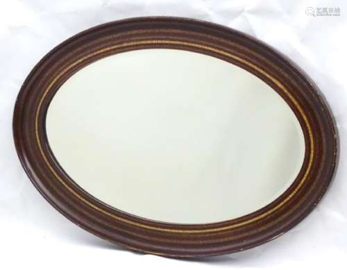A mid 20thC oval bevelled mirror with crossbanded