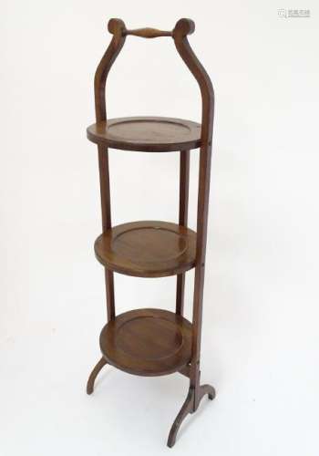 An early 20thC mahogany cake stand, with three dished