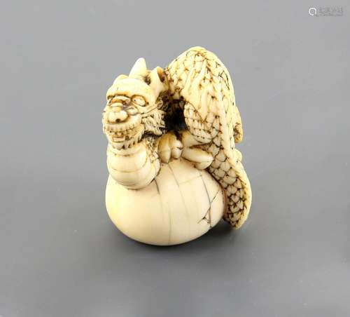 An ivory netsuke of a dragon coiled on a drum (or other object); inscribed with two kanji in a