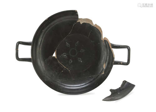 BLACK-GLAZED KYLIX, 4th CENTURY B.C. in rosy clay with black shining glaze, fragmentary. Measures